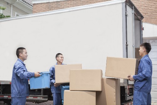 Movers carrying furniture through a London townhouse staircase